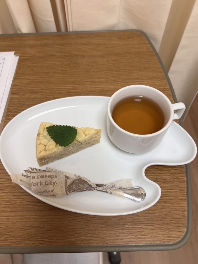 産後の入院中に提供されたおやつ。小さなケーキと紅茶が白いプレートにセットされている。