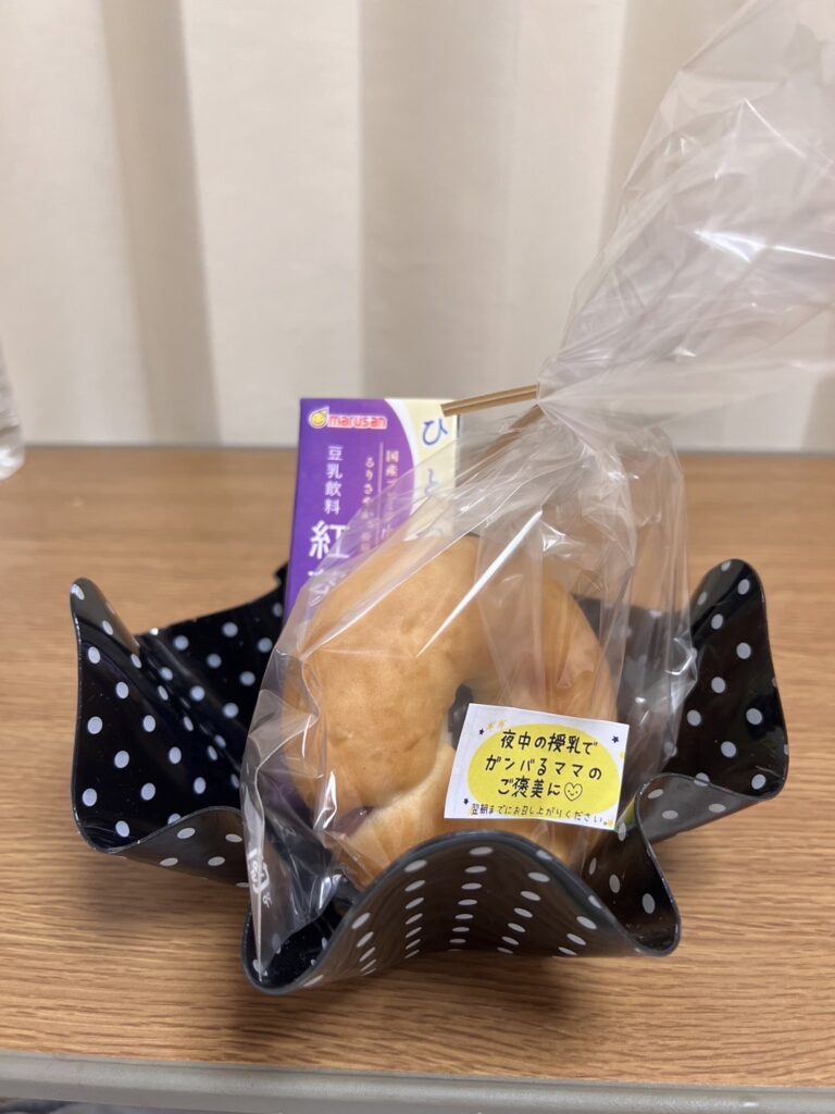 産後の入院中に提供された軽食。小さなパンと豆乳飲料が透明な袋に包まれ、メッセージが添えられている。