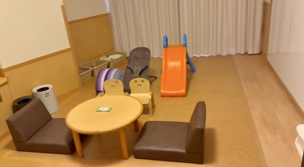 ホテルのキッズプレジャールーム内の遊びスペース。滑り台やローチェア、バウンサーが並んでいる。