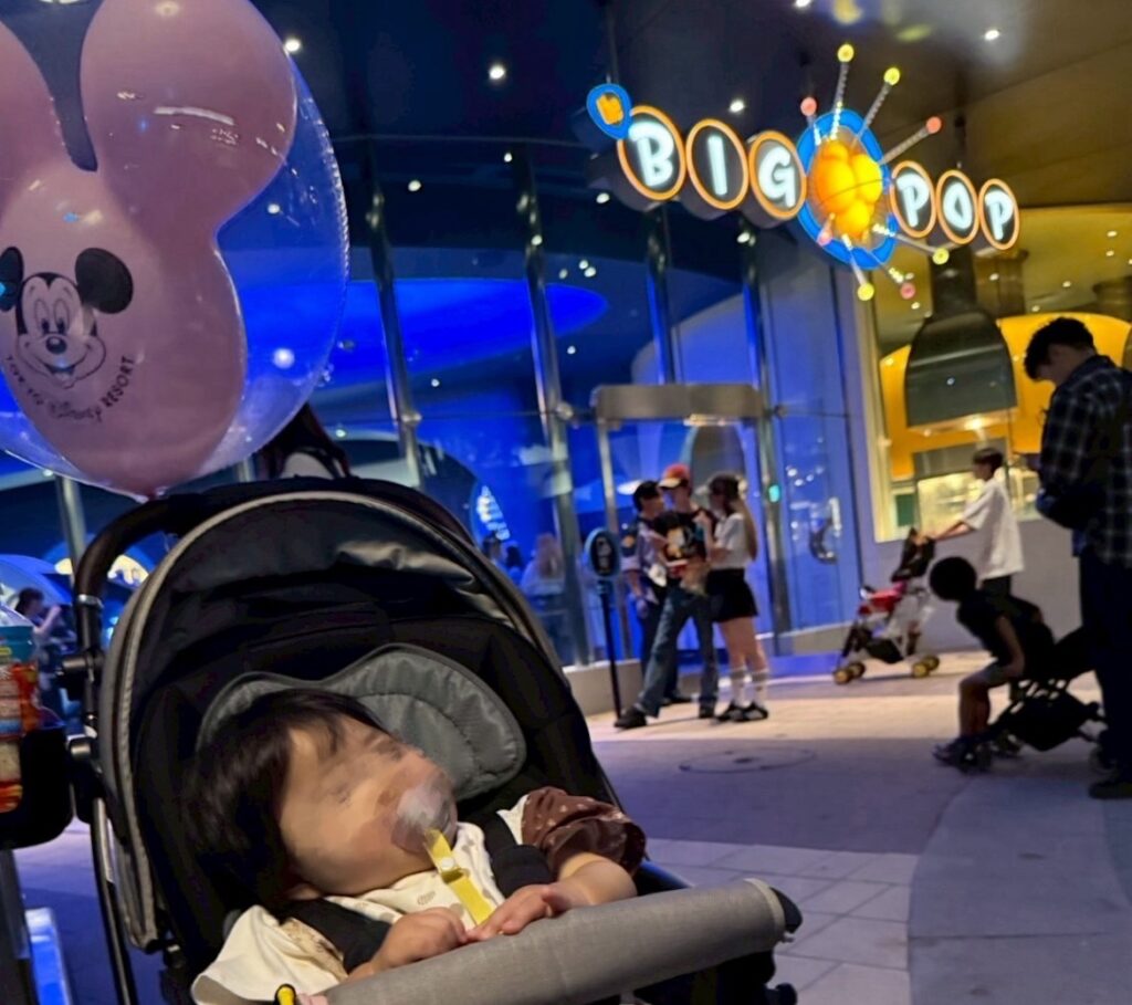 夜のBIG POP前でベビーカーに乗った赤ちゃんとミッキー風船。