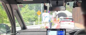 トンネル入口前で交通誘導員が立つ様子。前方には工事中のトンネルが見える。