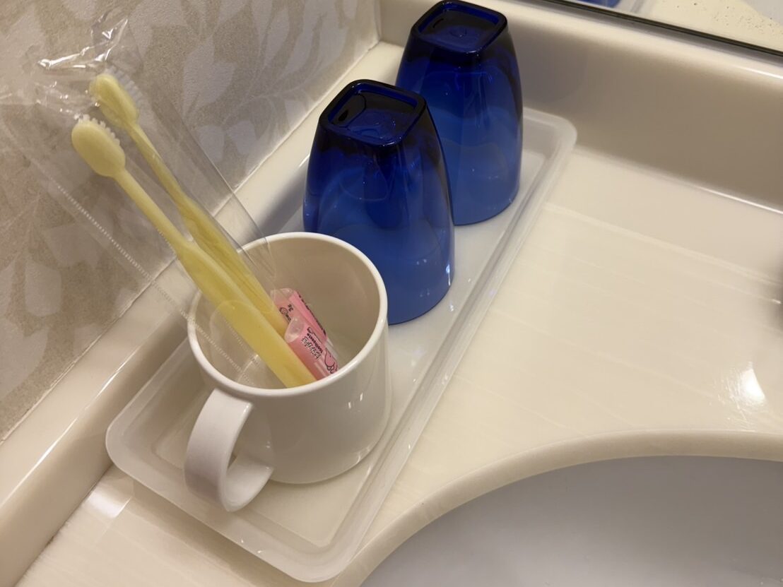 洗面台に並べられた青いコップと歯ブラシ